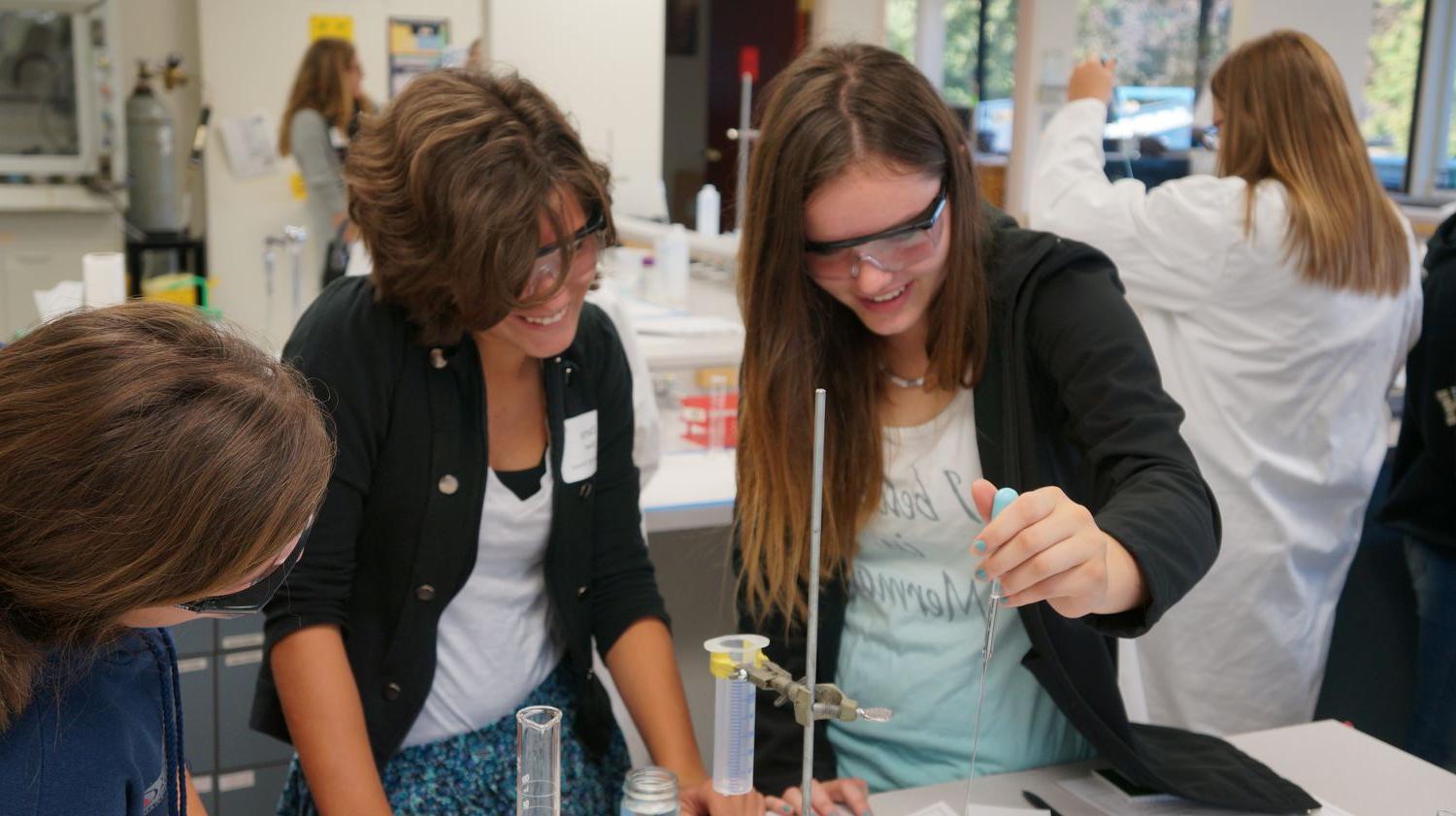 Young women running science experiments in a lab setting.