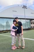 A mother and son stand on the practice field of the P1FCU-Kibbie Activity Center.